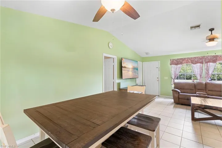Dining space with light tile patterned flooring, lofted ceiling, and ceiling fan