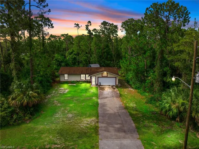 View of front facade with concrete driveway and a front yard