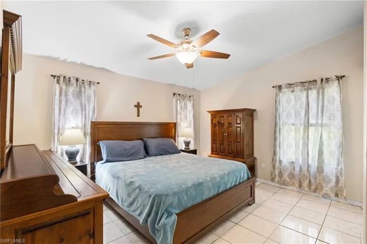 Bedroom with light tile patterned flooring, vaulted ceiling, and a ceiling fan