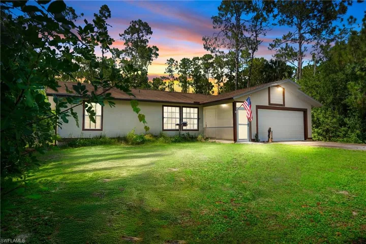 Ranch-style home with a garage, concrete driveway, a front yard, and stucco siding