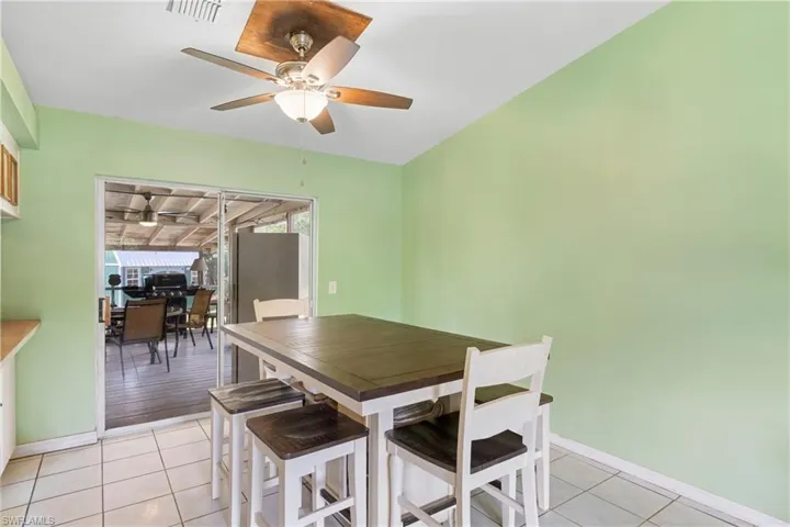 Dining space with light tile patterned flooring and a ceiling fan