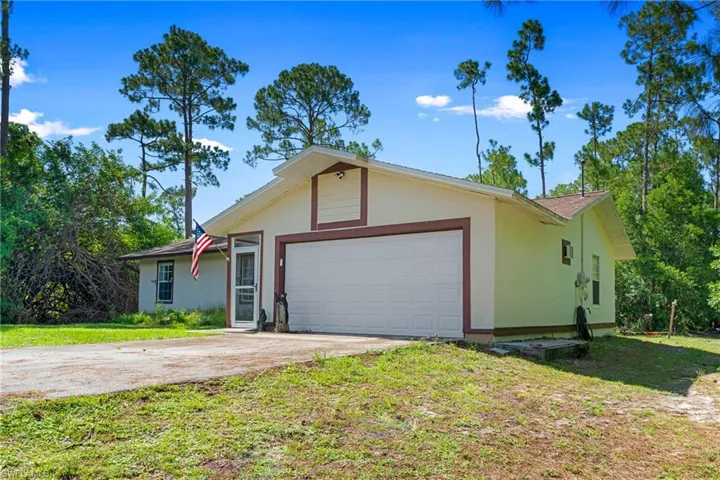 Ranch-style house with concrete driveway, a garage, stucco siding, and a front yard
