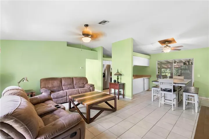 Living room featuring a ceiling fan, light tile patterned floors, and vaulted ceiling