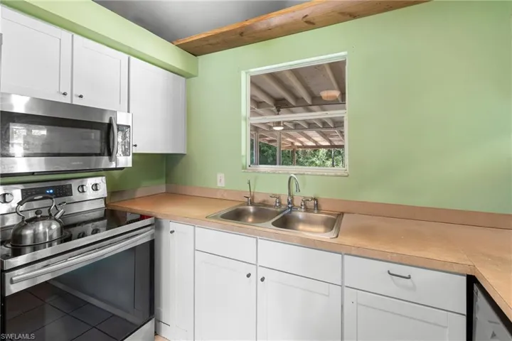 Kitchen featuring stainless steel appliances, white cabinets, light countertops, and tile patterned floors