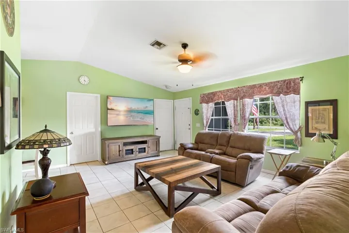 Living area featuring lofted ceiling, ceiling fan, and light tile patterned flooring