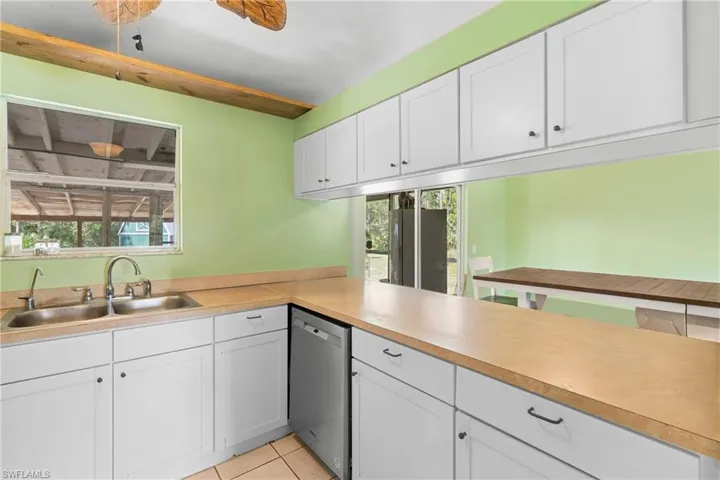 Kitchen with dishwasher, white cabinets, light countertops, and light tile patterned floors