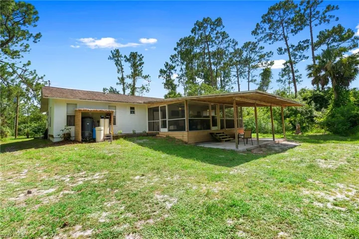 Rear view of house with a sunroom, a patio, and a yard