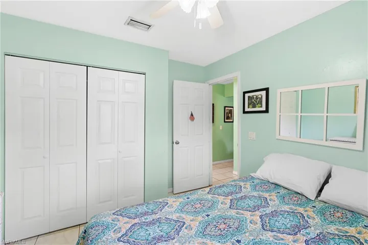Bedroom featuring a closet, light tile patterned floors, and ceiling fan