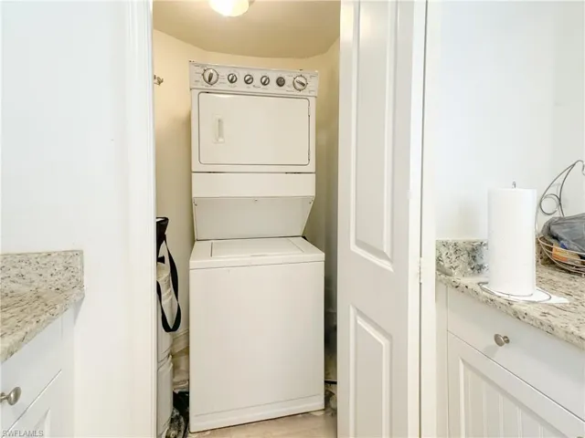 Laundry area with light tile patterned floors and stacked washer and dryer