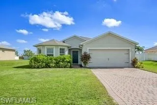Single story home featuring decorative driveway, a front lawn, a garage, and stucco siding