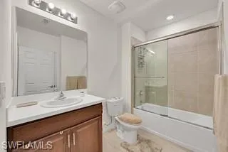 Full bath with bath / shower combo with glass door, vanity, and recessed lighting