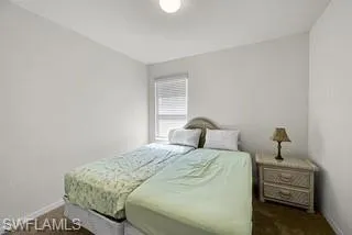 Bedroom featuring dark carpet and baseboards