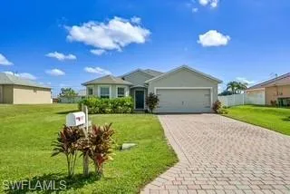 Ranch-style house featuring a front lawn, decorative driveway, and an attached garage