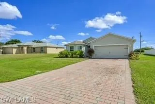 Single story home featuring a front yard, decorative driveway, and a garage