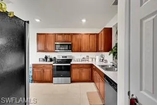 Kitchen with stainless steel appliances, brown cabinets, light countertops, light tile patterned flooring, and recessed lighting