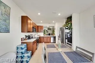Kitchen with light countertops, brown cabinets, stainless steel appliances, recessed lighting, and light tile patterned floors