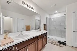Bathroom featuring double vanity, light tile patterned floors, and a stall shower