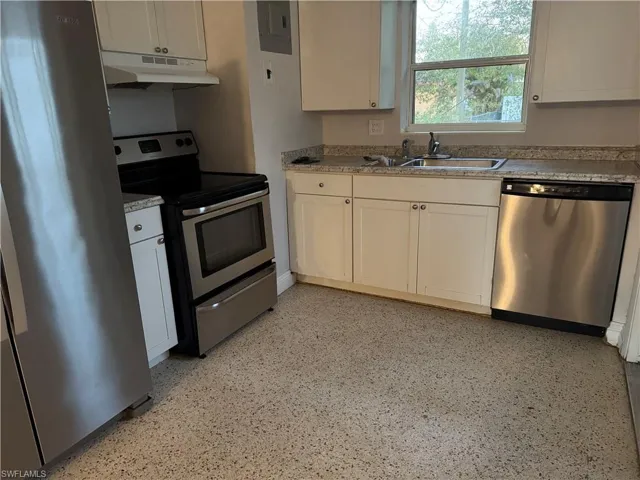 Kitchen with stainless steel appliances, light countertops, and white cabinetry