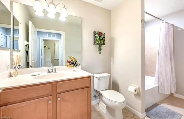 Full bath featuring shower / tub combo with curtain, vanity, light tile patterned floors, and a chandelier