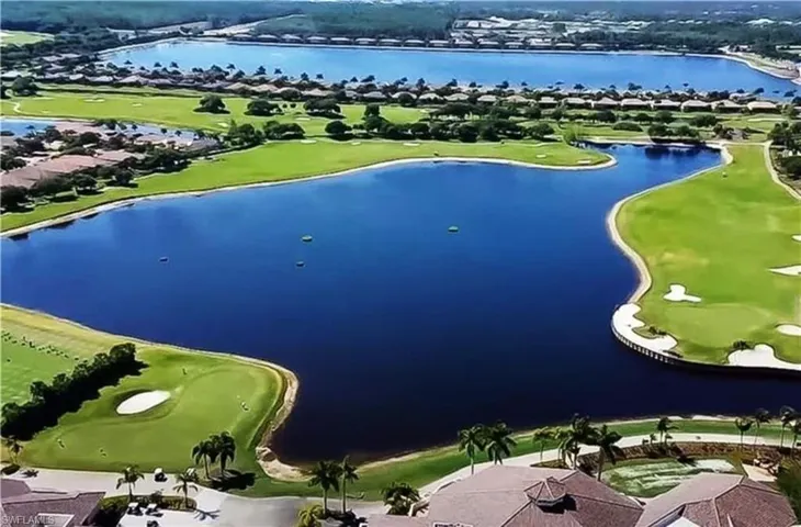 Aerial perspective of suburban area featuring a local golf course and a nearby body of water