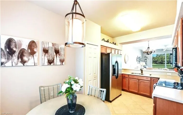 Kitchen featuring hanging light fixtures, light countertops, stainless steel fridge with ice dispenser, a chandelier, and black microwave