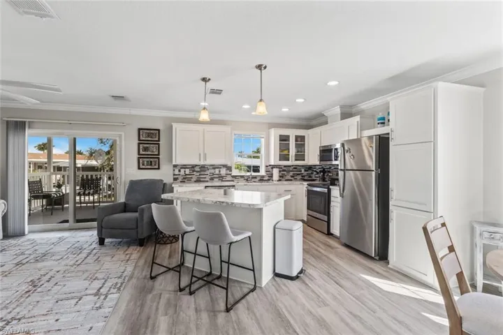 Kitchen featuring a breakfast bar, ornamental molding, stainless steel appliances, glass insert cabinets, and a kitchen island
