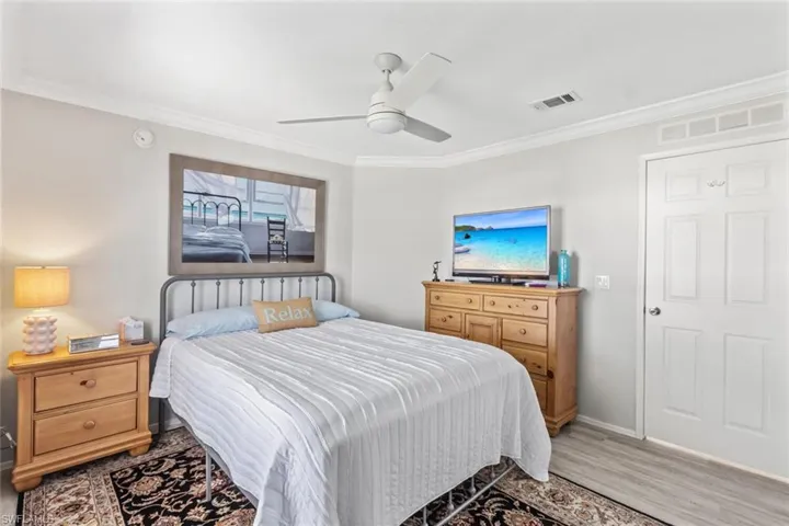 Bedroom featuring ornamental molding, ceiling fan, and wood finished floors