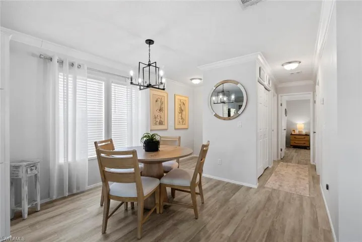 Dining space featuring ornamental molding, light wood finished floors, and a chandelier