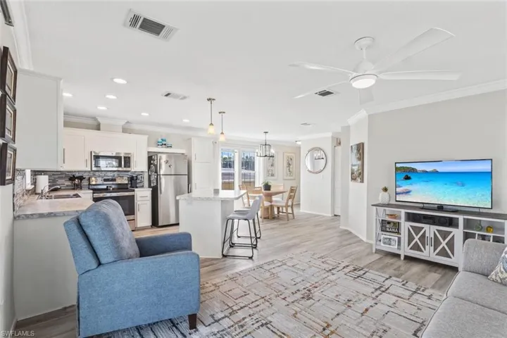 Living area with crown molding, a ceiling fan, light wood-style floors, recessed lighting, and a chandelier