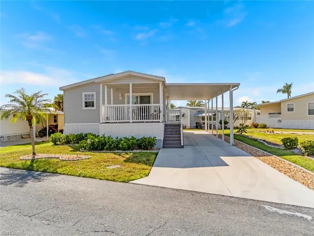 Manufactured / mobile home with a porch, driveway, a front lawn, and a carport