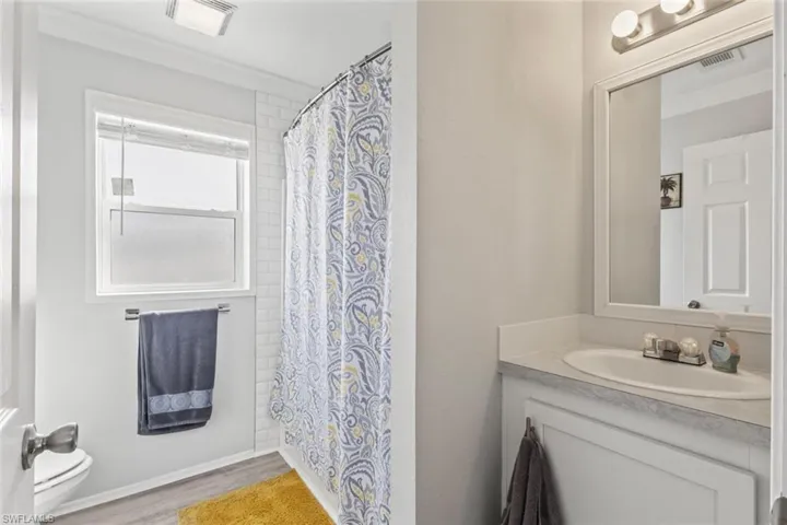 Bathroom with vanity, light wood-type flooring, and shower / bath combo with shower curtain