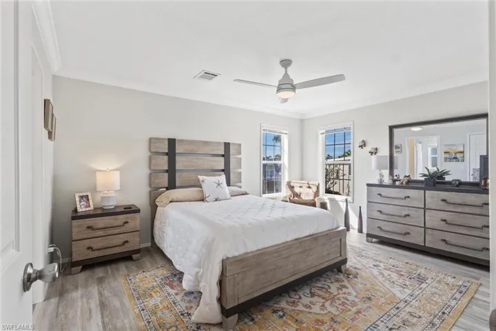 Bedroom featuring light wood finished floors, ceiling fan, and crown molding