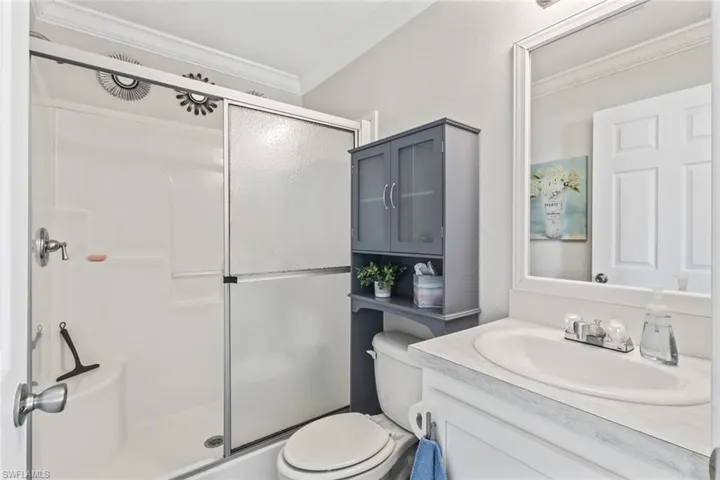 Bathroom with crown molding, vanity, and a stall shower