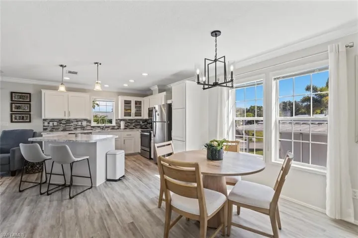 Dining room featuring light wood finished floors, a chandelier, ornamental molding, and recessed lighting