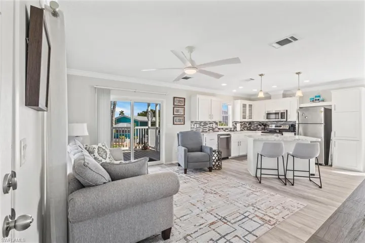Living room featuring ornamental molding, a ceiling fan, light wood-style flooring, and recessed lighting