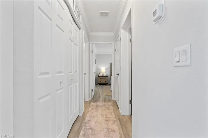Hallway featuring light wood finished floors and ornamental molding