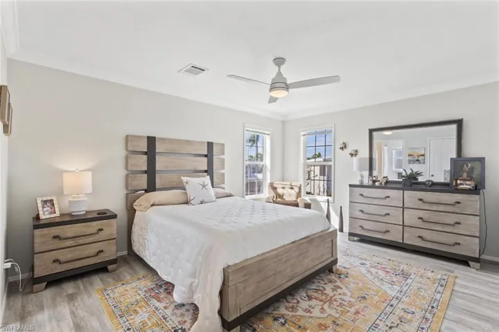 Bedroom featuring light wood-style flooring, ornamental molding, and a ceiling fan