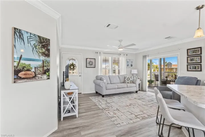 Living room with ornamental molding, light wood finished floors, and a ceiling fan
