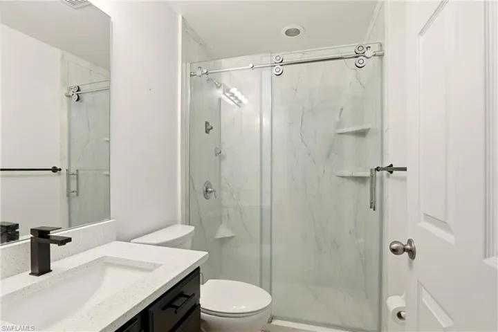 Walk-in shower with sliding glass door and integrated shelving