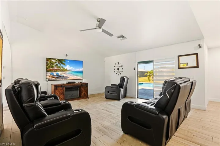 Vaulted ceilings with a ceiling fan, light wood-finish flooring, sliding glass door, and a visible pool