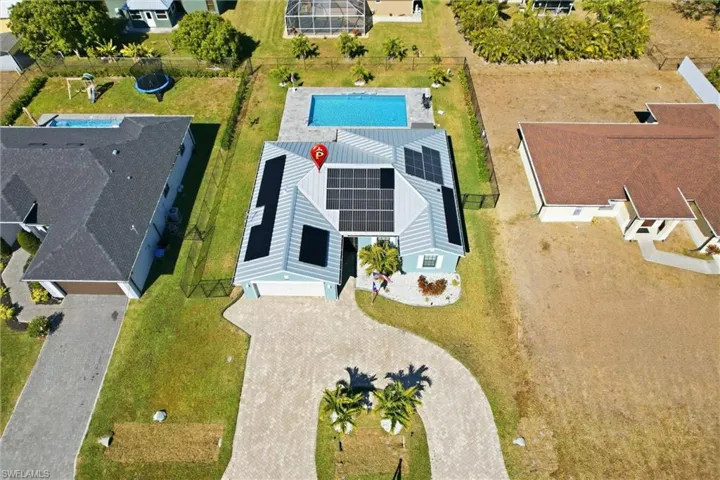 Exterior featuring a private pool, an expansive paved driveway, multiple solar panels, and mature landscaping