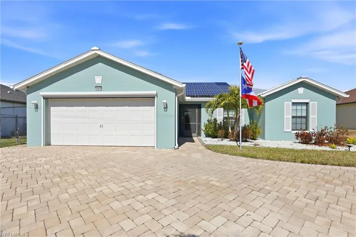 Paver driveway leading to a two-car garage with a roll-down hurricane shutter