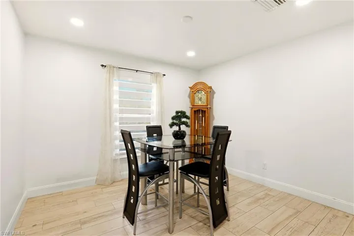 Recessed lighting, wood-finish flooring, and a single window with horizontal blinds