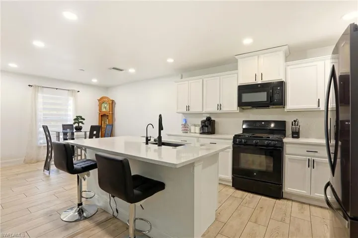 Modern kitchen featuring white cabinetry, light-toned countertops, and a central island with a built-in sink
