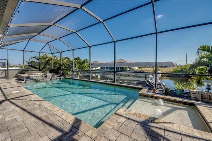 View of swimming pool with a lanai, a sunroom, boat lift, a pool with connected hot tub, and a boat dock