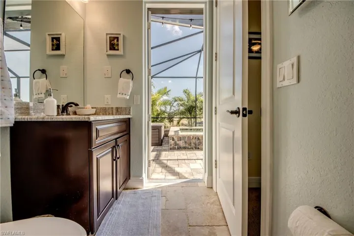 Half bath featuring vanity, a textured wall, and stone tile floors
