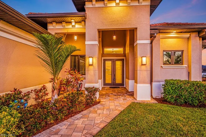 Property entrance with stucco siding, a yard, and french doors