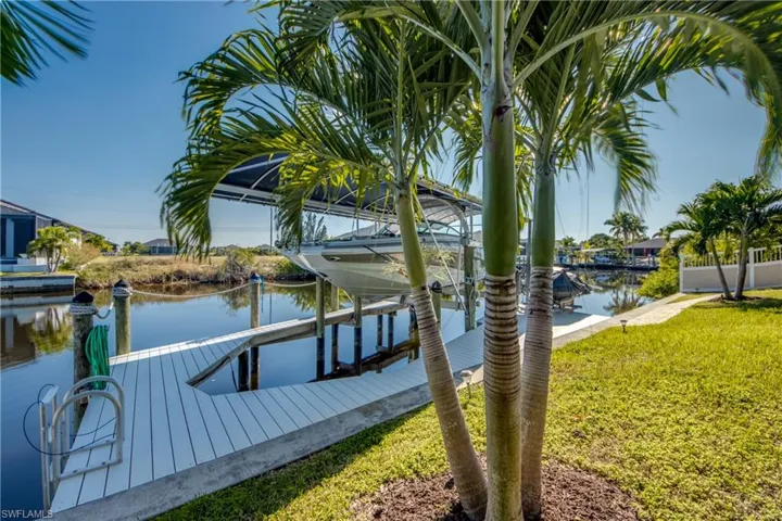 Dock area featuring boat lift, a water view, and a yard