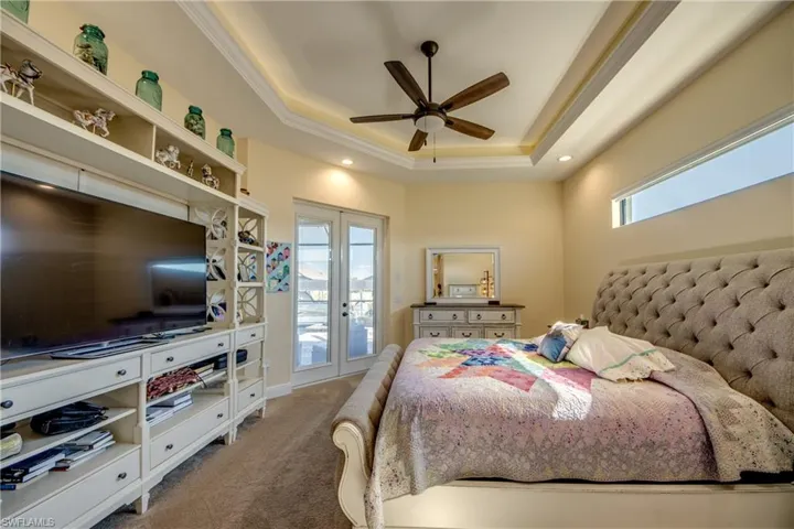 Bedroom with french doors, carpet flooring, a tray ceiling, ceiling fan, and access to exterior