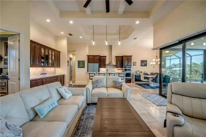 Living area with stone tile flooring, recessed lighting, a tray ceiling, ceiling fan, and a towering ceiling